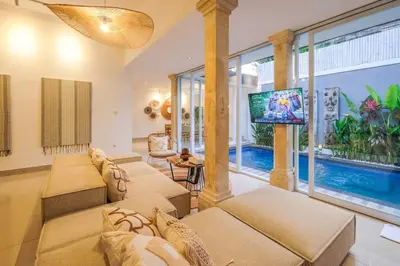 a living room with couches and a tv and a pool at Casa De Beji Seminyak in Seminyak