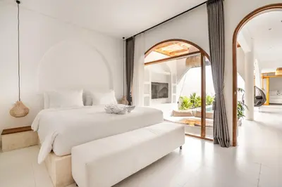 a white bedroom with a large bed and a large mirror at La Feliz Villa Seminyak in Seminyak