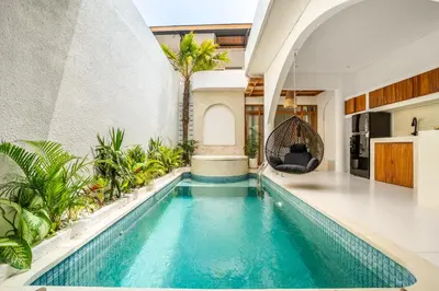 an indoor pool with a swing in a house at La Feliz Villa Seminyak in Seminyak