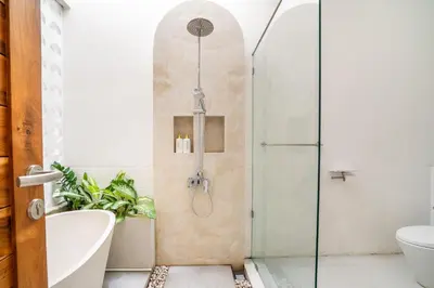 a bathroom with a shower and a tub and a toilet at La Feliz Villa Seminyak in Seminyak