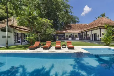 a swimming pool with lounge chairs and a house at Villa Eight in Seminyak