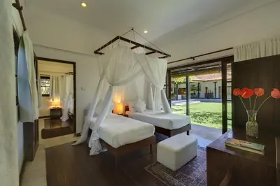 a bedroom with two beds and a canopy bed at Villa Eight in Seminyak