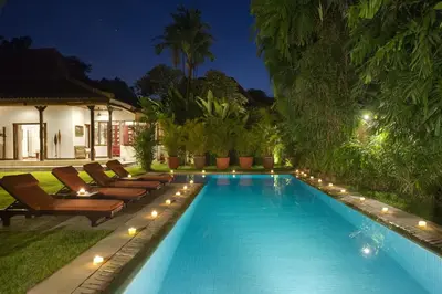 a swimming pool with lounge chairs next to a house at Villa Eight in Seminyak