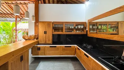 a kitchen with wooden cabinets and black counter tops at Villa Sukacita - Family Friendly 4BR Seminyak Eat Street 900m Walk To Beach in Seminyak