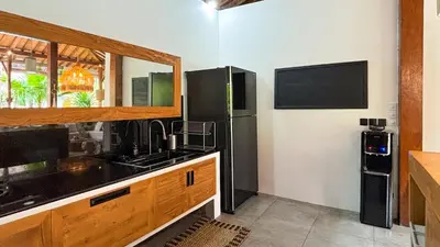 a kitchen with a sink and a black refrigerator at Villa Sukacita - Family Friendly 4BR Seminyak Eat Street 900m Walk To Beach in Seminyak