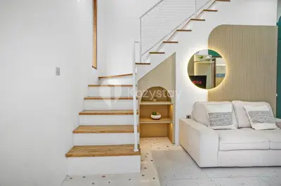 a living room with a white couch and stairs at Calisee Villa by Kozystay - Denpasar in Seminyak