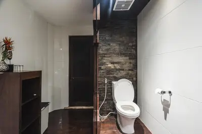 a bathroom with a toilet and a brick wall at Timang Villa, Jimbaran-Bali in Jimbaran