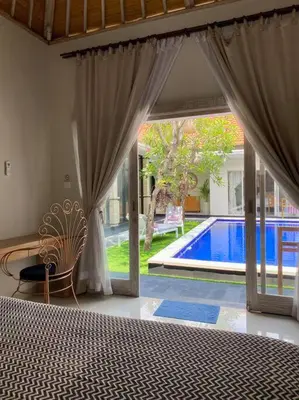 a bedroom with a bed and a view of a swimming pool at Tranquil Family Villa Retreat in Umalas in Kerobokan