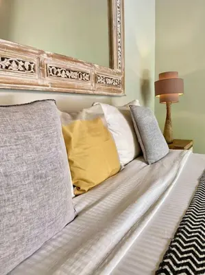 a bed with pillows and a mirror on the wall at Tranquil Family Villa Retreat in Umalas in Kerobokan