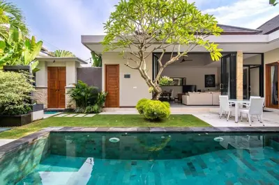 a villa with a swimming pool in front of a house at Cozy villa in Umalas in Kerobokan