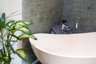 a bathroom with a white bath tub and a plant at Cozy villa in Umalas in Kerobokan