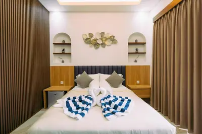 a bedroom with a bed with blue and white pillows at The Lavana Sahadewa Villa Kuta Sunset in Legian