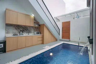 an indoor swimming pool in a house with a staircase at The Lavana Sahadewa Villa Kuta Sunset in Legian