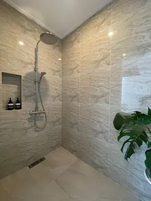 a shower in a bathroom with a stone wall at New 2BR Villa Private Pool Near Seminyak in Kerobokan