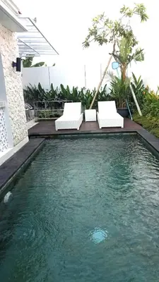 a swimming pool with two chairs and some water at New 2BR Villa Private Pool Near Seminyak in Kerobokan