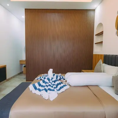 a bedroom with two beds and a wall with aiger at The Lavana Nakula Villa Kuta Sunset in Kuta
