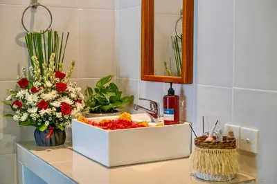 a bathroom counter with a sink with flowers on it at Arts Tamansari Villa Two-Bedroom Private Pool Kuta in Kerobokan