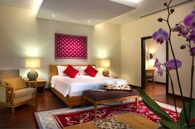 a bedroom with a bed and a chair and a mirror at Bintang Bali Villa in Kuta