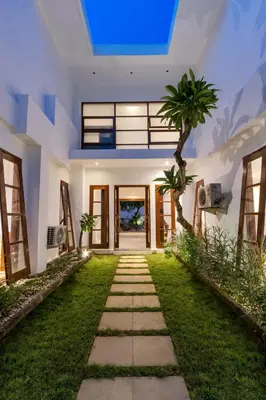 a walkway in a house with a palm tree at Villa Lilja in Seminyak