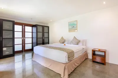 a bedroom with a large white bed and a table at Villa Lilja in Seminyak