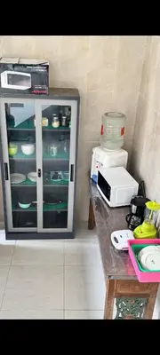 a counter with a glass cabinet with dishes in it at narayuka house in Seminyak