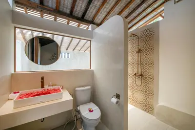 a bathroom with a toilet and a mirror at Sunset Joglo Pool Villa in Kerobokan