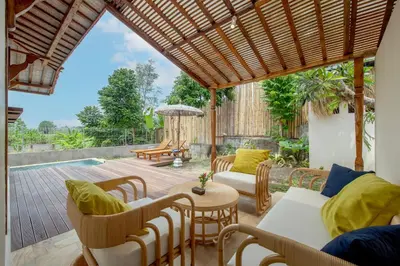 a patio with a table and chairs and a pool at Sunset Joglo Pool Villa in Kerobokan