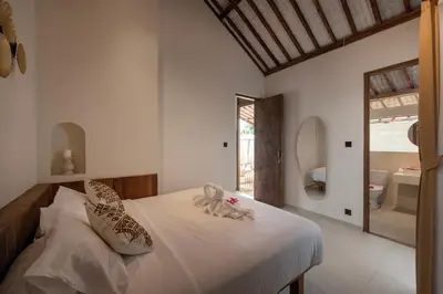 a bedroom with a bed and a mirror and a bathroom at Sunset Joglo Pool Villa in Kerobokan