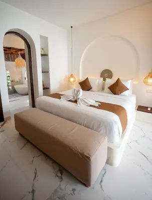 a large bedroom with two beds and a bench in it at Sueño Villa Seminyak in Seminyak