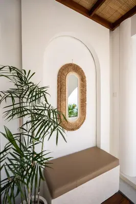 a bench in a room with a mirror and a plant at Sueño Villa Seminyak in Seminyak