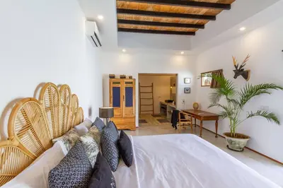 a bedroom with a white bed with a wooden headboard at Villa Jannu by DreamAwayBali in Seminyak