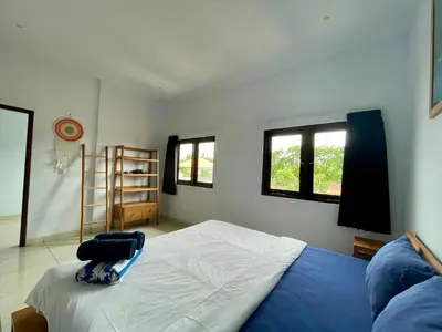 a bedroom with a bed and two windows at Family Villa with Private Pool in Central Seminyak in Seminyak