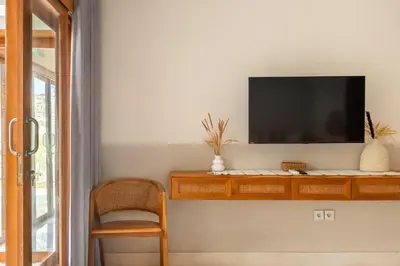 a living room with a tv on a wall at Wayang Villa by Betterplace in Kerobokan