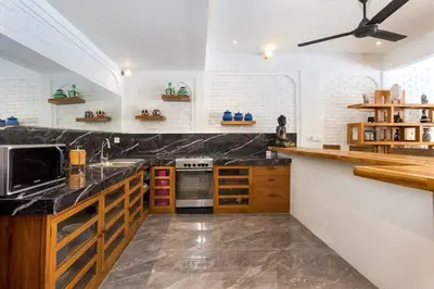 a kitchen with black marble counter tops and a ceiling fan at Villa Julietta, 4 BR in the heart of Seminyak in Seminyak