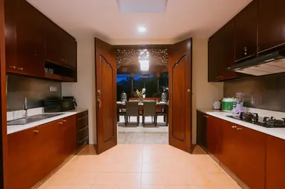 a kitchen with wooden cabinets and a dining room at Villa Anggrek Jimbaran in Jimbaran