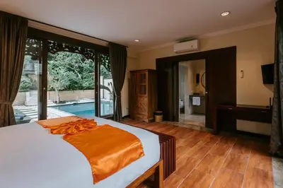 a bedroom with a bed with an orange blanket on it at Villa Anggrek Jimbaran in Jimbaran