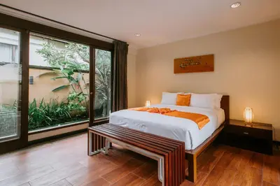 a bedroom with a bed and a large window at Villa Anggrek Jimbaran in Jimbaran