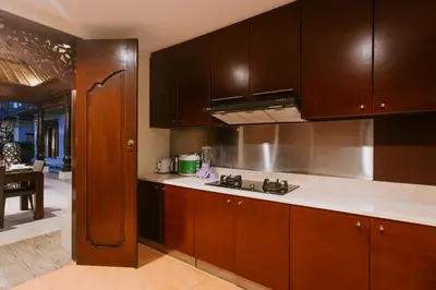 a kitchen with wooden cabinets and white counter tops at Villa Anggrek Jimbaran in Jimbaran