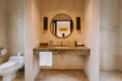 a bathroom with a sink and a toilet and a mirror at Villa Anggrek Jimbaran in Jimbaran