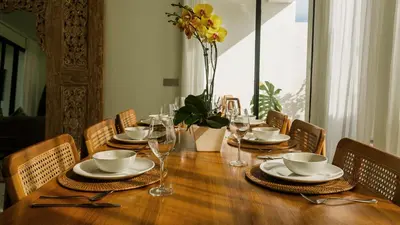 a wooden table with plates and wine glasses on it at Sunset D1 Villa by Betterplace in Kerobokan