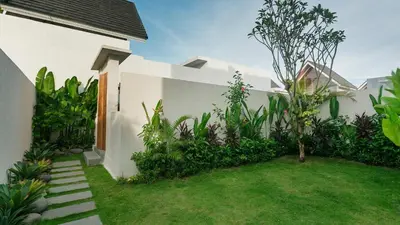 a white house with a green yard with a lawn at Sunset D1 Villa by Betterplace in Kerobokan