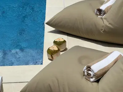 a bed with pillows on the floor next to a pool at LUX 3 Bedroom Villa 5min Walk to the Beach in Canggu
