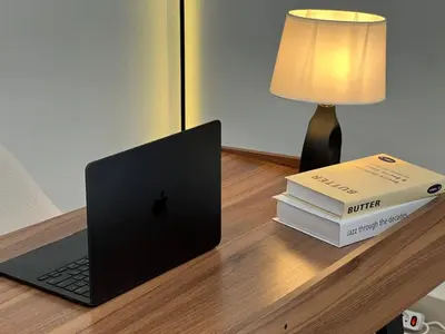 a laptop computer sitting on a desk next to two books at Nomadic LUX villa in Canggu