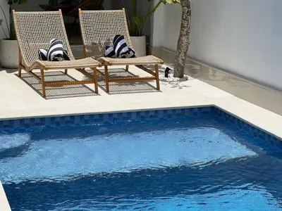 two chairs sitting next to a swimming pool at Nomadic LUX villa in Canggu