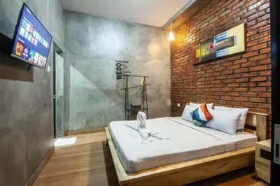a bedroom with a large bed with a brick wall at Mantra Guesthouse in Denpasar