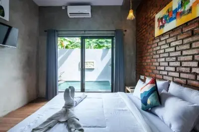 a bedroom with a large bed and a brick wall at Mantra Guesthouse in Denpasar