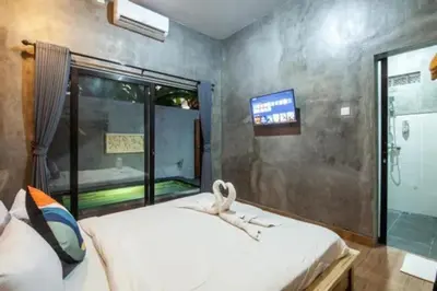 a bedroom with a white bed and a tv at Mantra Guesthouse in Denpasar