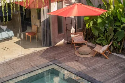 a patio with an umbrella and chairs and a pool at Artistic 4BD Villa with Private Pool & Jungle Vibes in Seminyak