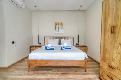 a bedroom with a bed with two blue pillows on it at Nirvana Villa 3BR Brand New in Umalas, Canggu in Kerobokan