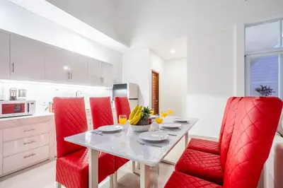 a white kitchen with red chairs and a table with drinks at Brand new luxury minimalistic villa The Toy with 3 bedrooms in Kerobokan